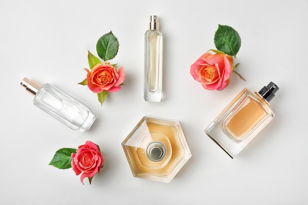 Composition with transparent bottles of perfume and beautiful flowers on white background