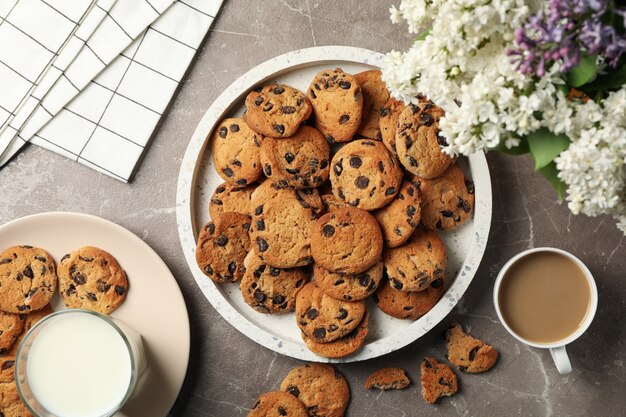 Composition with tray of chocolate chip cookies on light brown table. Sweet breakfast