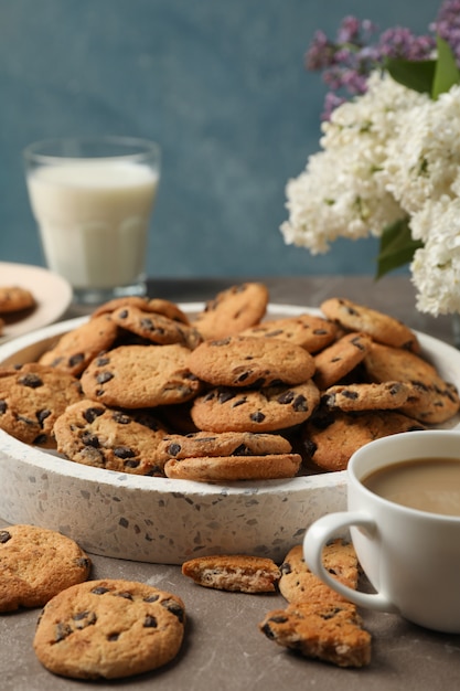 Composition with tray of chocolate chip cookies on light brown table. Sweet breakfast