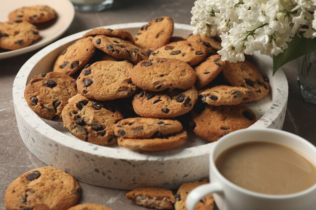 Composition with tray of chocolate chip cookies on light brown table. Sweet breakfast