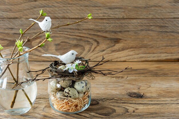 Composition with twig nest, quail eggs and small birds. Easter holidays in rustic style.