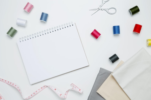composition with various threads and sewing accessories on white background mock up notebook