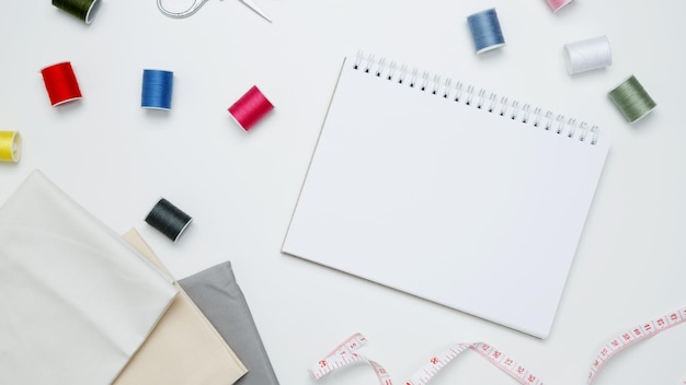 composition with various threads and sewing accessories on white background mock up notebook