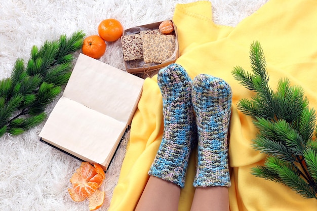 Composition with warm plaid, book,k and female legs, on color carpet background