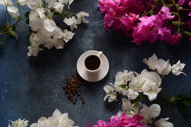 Foto composizione con tazza di caffè bianca, fagioli e fiori come sfondo