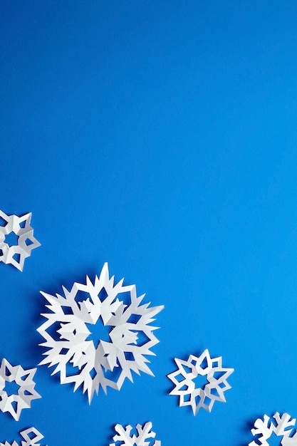 Composition with white paper snowflakes on blue