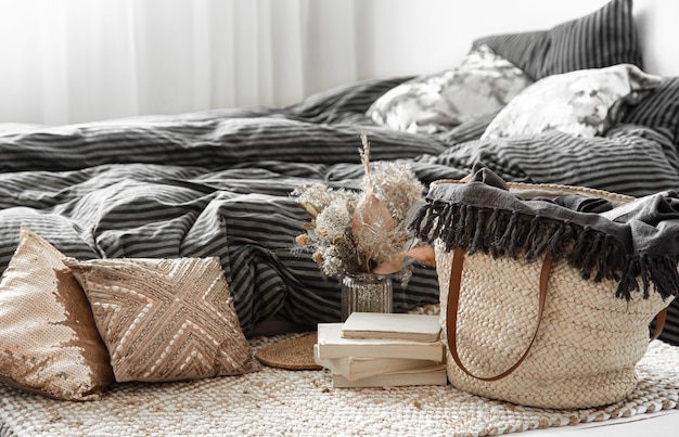 Photo composition with wicker straw large bag, and decorative elements on a bedroom.