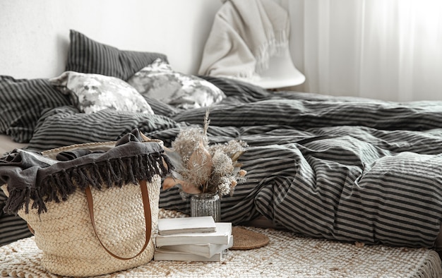 Composition with wicker straw large bag, and decorative elements in a bedroom.