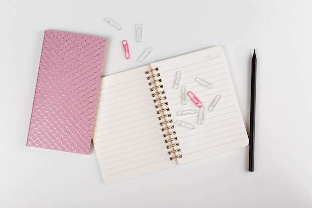 Composition with womens business accessories. note pad, pencil, paper clips on white background. top view. flat lay.