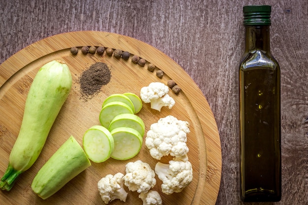 Composition on wooden background organic vegetarian foods: zucchini, cauliflower, black pepper. The view from the top. Copy space for your text