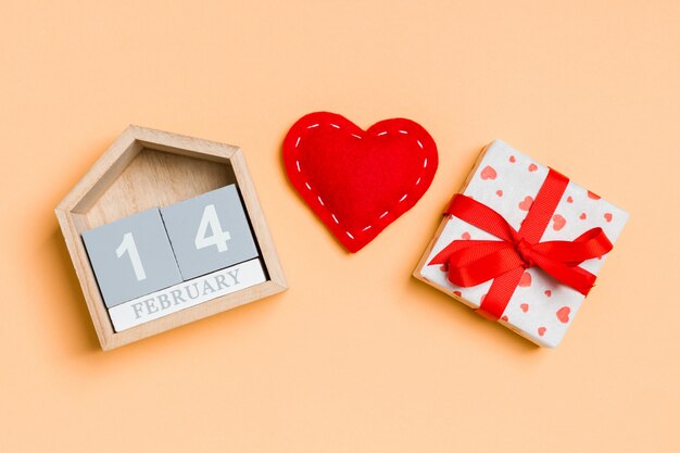 Composition of wooden calendar, holiday white gift boxes and red textile hearts on colorful  . The fourteenth of February. Valentine's day  