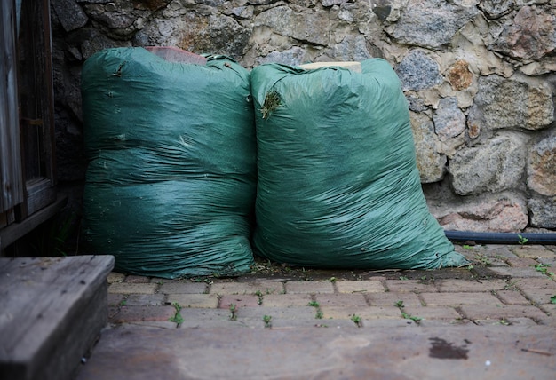 Compost in enorme groene zakken naast het hek van een landhuis Ecologische meststoffen voor planten