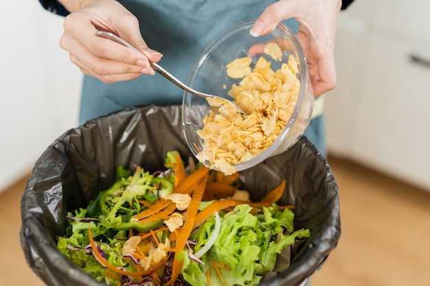写真 生ごみのリサイクル有機食品を堆肥化アジアの若い家庭の女性が野菜からゴミ箱に食べ物の残り物を投げてこする環境に責任のある生態学
