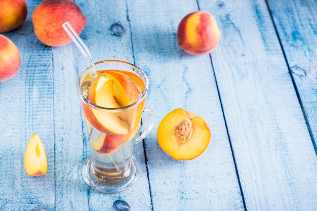 Compote of fresh peaches in a glass with a straw on the table Summer organic drinks