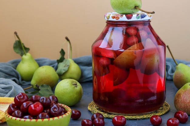 Compote of pears and cherries in jar on table, harvest for the winter, horizontal photo