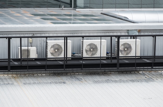 The compressor unit row of the air conditioner system on the top of the modern commercial building,  working all day in the summer, front view with the copy space.