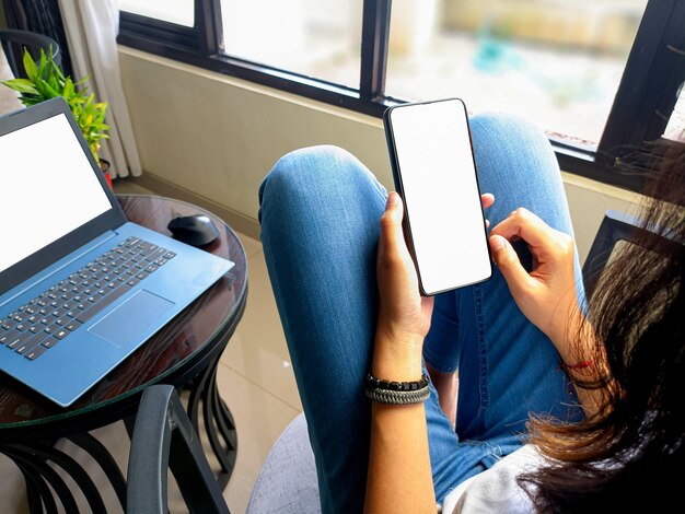 Computer blank screen phone mockup image with white background\
for advertising woman39s hand using laptop and mobile phone on\
table in cafemockup