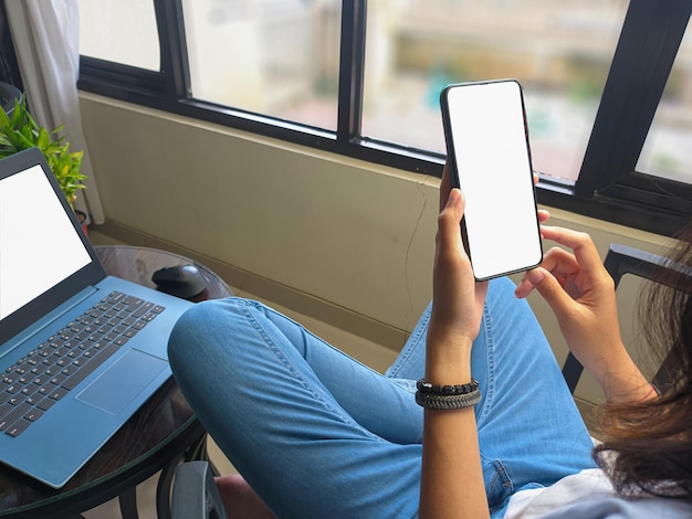 Computer blank screen phone mockup image with white background\
for advertising woman39s hand using laptop and mobile phone on\
table in cafemockup