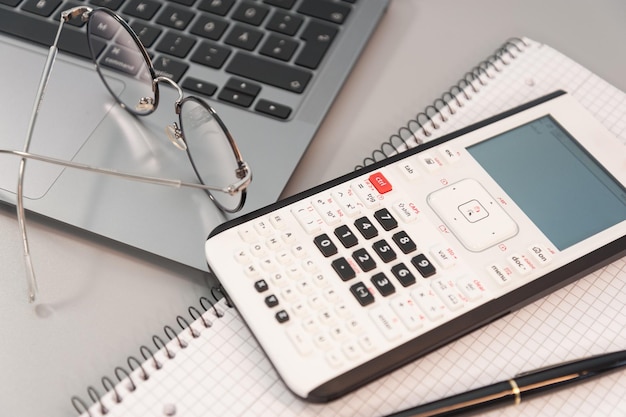 Photo computer calculator and notepad with pen on gray background