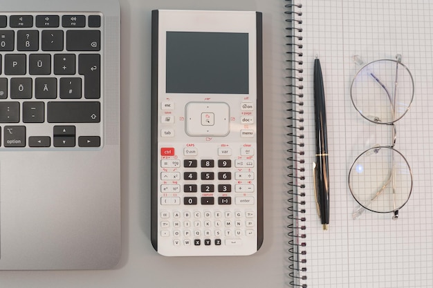 computer calculator and notepad with pen on gray background