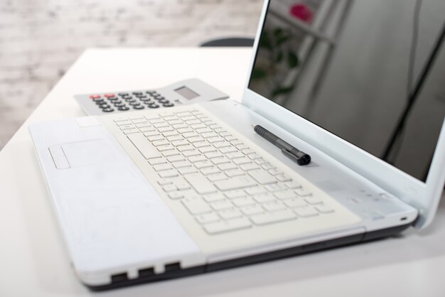 A computer, a calculator and a pen on a desk