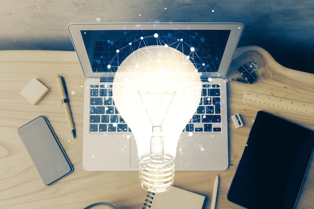 Foto computer sul desktop in ufficio con icona della lampadina ologramma esposizione multipla concetto di idea