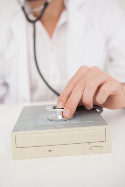 Computer engineer listening to harddrive with stethoscope