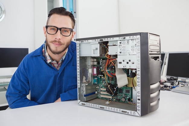 Computer engineer smiling at camera beside open console