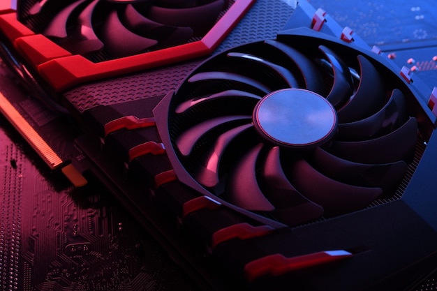 Computer game graphics card, videocard with two coolers on circuit board ,motherboard table. Close-up. With red-blue lighting.