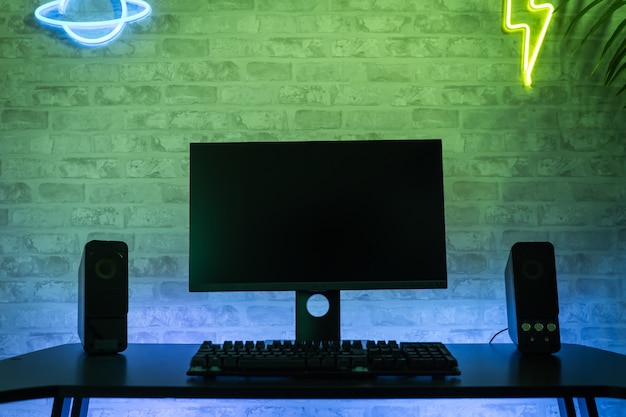 Фото Рабочее пространство компьютерного геймера с черным экраном монитора с неонами и яркими огнями gamer rig