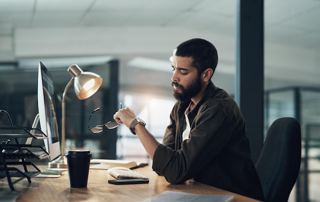 Computer graphic design and watch with man in office for website coding or programming deadline Business checking time and late with annoyed programmer employee in creative workplace for overtime