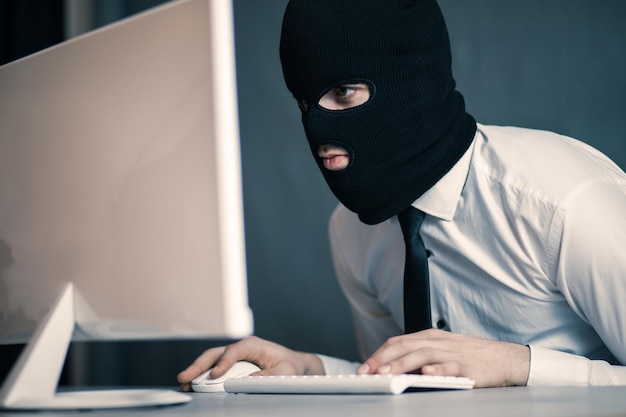 Computer hacker wearing mask on laptop computerxA