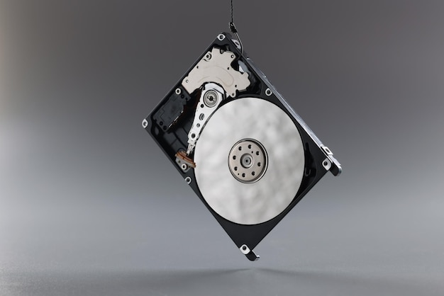 Computer hard disk drive on hook black hardware disk memory storage cylinder on grey background