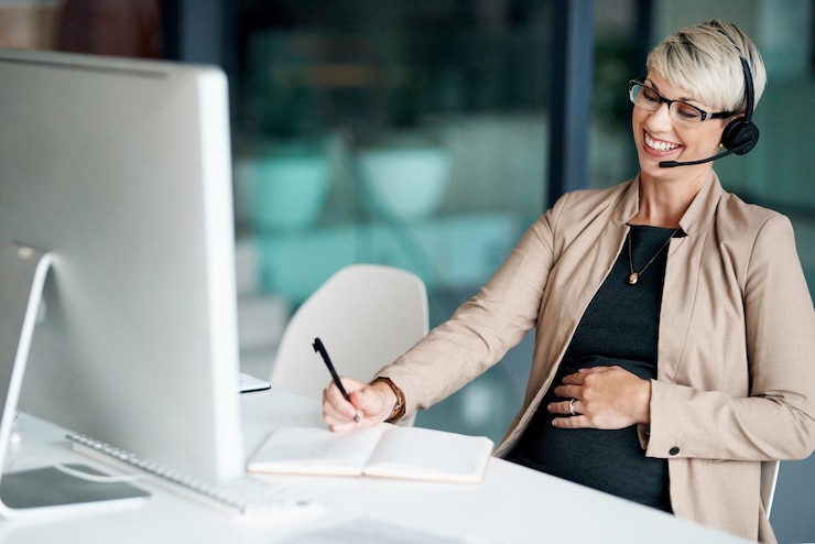 Foto computer headset and businesswoman writing notes in office for client appointment schedule technology contact and pregnant female virtual assistant with online administration task for company