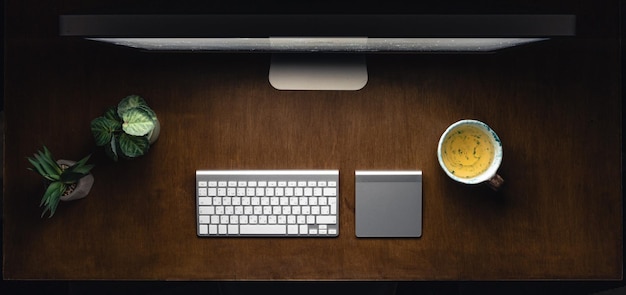 Компьютерная клавиатура и чашка чая на деревянном столе ночью