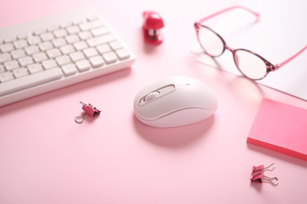 Photo computer keyboard and mouse glasses stickers stapler on pink background