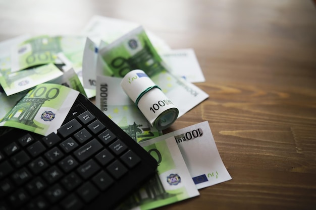 Computer keyboard and a scattering of 100 euro bills on the table The work of a programmer and blogger on the Internet