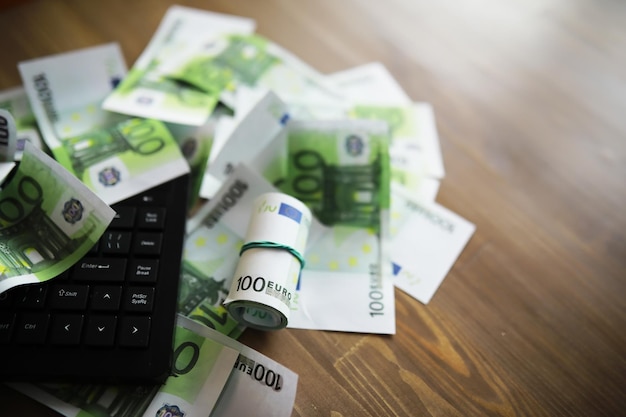 Computer keyboard and a scattering of 100 euro bills on the table The work of a programmer and blogger on the Internet