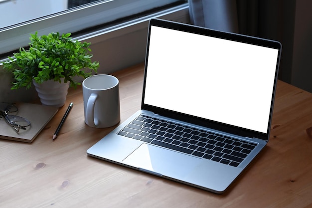 Computer laptop coffee cup notebook an houseplant on wooden table