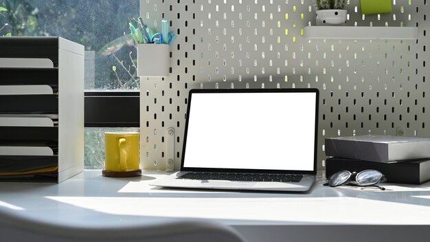 밝은 홈 오피스의 흰색 테이블에 있는 컴퓨터 노트북 커피 컵과 용품