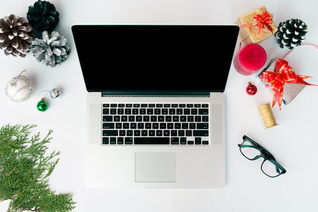 Foto display del computer portatile sul tavolo con schermo bianco isolato per mockup nel periodo natalizio. albero di natale, regali, decorazioni sullo sfondo.