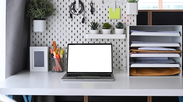 Computer laptop en kantoorbenodigdheden op witte tafel.