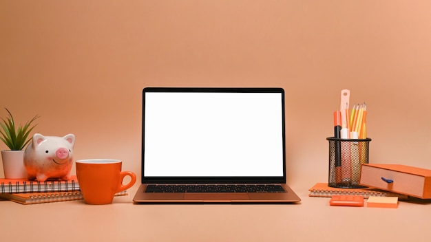 Computer laptop met leeg scherm en oranje accessoires beige achtergrond
