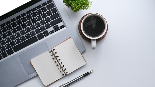 Computer laptop, notebook en kopje koffie op eenvoudige werkruimte.