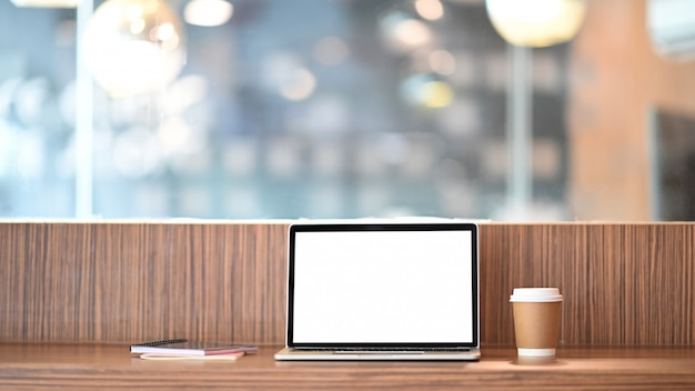 흰색 빈 화면이 테이크 아웃 커피 컵과 현대적인 카페 위에 노트북 나무 카운터 바에 컴퓨터 노트북 질서 / 편안한 직장 개념입니다.