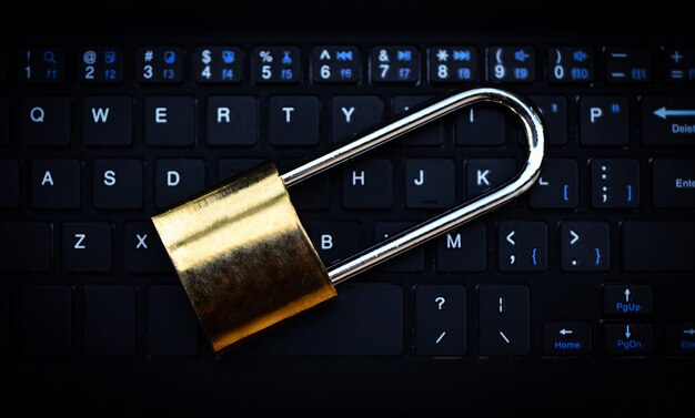Foto computer met gegevensbeveiligingssystemen met vergrendeld hangslot op toetsenbord voor bescherming van criminaliteit door een anoniem hacker-internet en datanetwerk