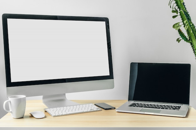 Computer monitor with  white screen on office table with supplies