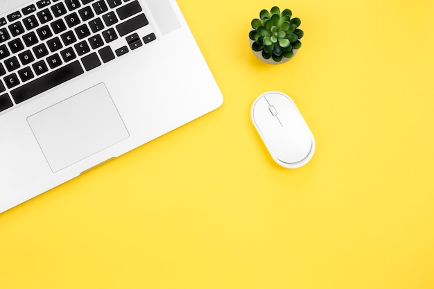 Computer mouse and laptop on a yellow background isolated flat lay