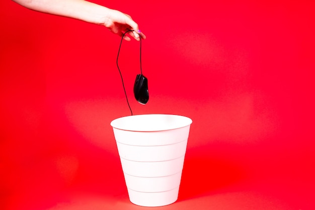 A computer mouse with a wire is thrown into the office wastebasket