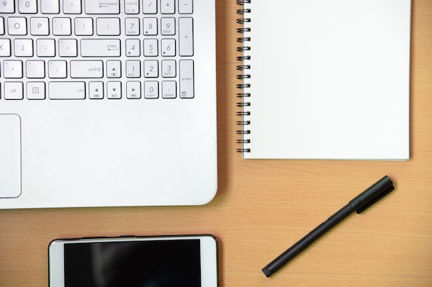 Computer notebook with smartphone notebook message and a pen on working desk in office